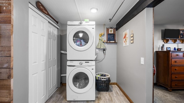 washroom featuring laundry area, stacked washer and dryer, wood finished floors, and baseboards