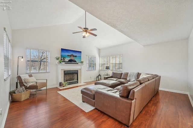 living room featuring a tiled fireplace, a ceiling fan, wood-type flooring, and a healthy amount of sunlight