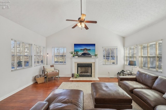 living room featuring a textured ceiling, wood finished floors, a ceiling fan, and a tiled fireplace