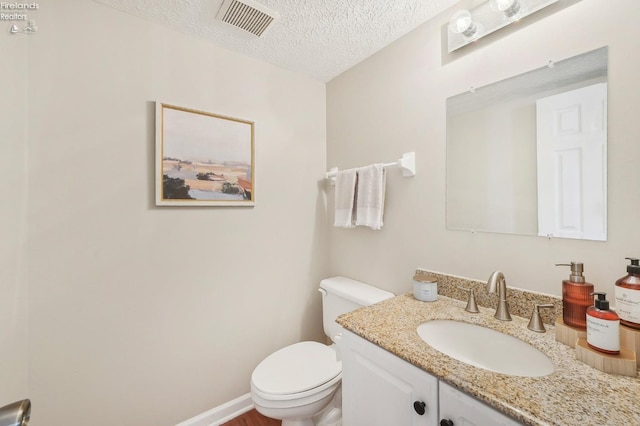 bathroom with visible vents, baseboards, toilet, vanity, and a textured ceiling