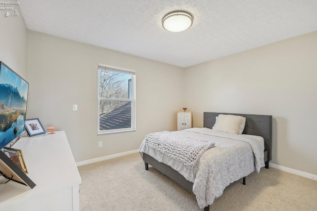 bedroom featuring light carpet, a textured ceiling, and baseboards