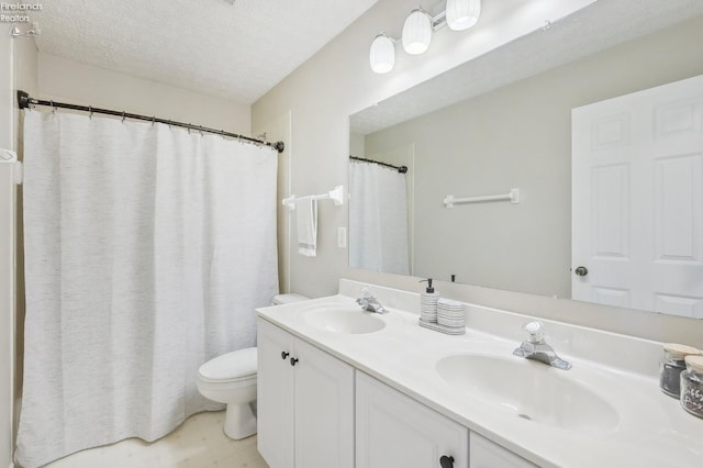 bathroom featuring a sink, a textured ceiling, double vanity, and toilet