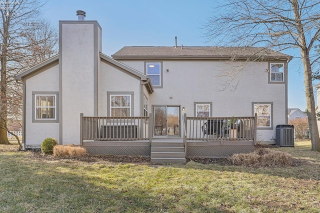 back of house with stucco siding, a lawn, a deck, central AC unit, and a chimney