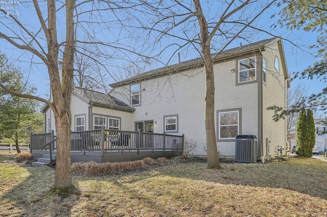 rear view of property with stucco siding, central air condition unit, a yard, and a deck