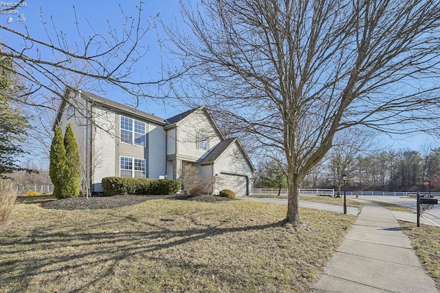 view of property exterior with fence, stucco siding, a garage, a yard, and driveway