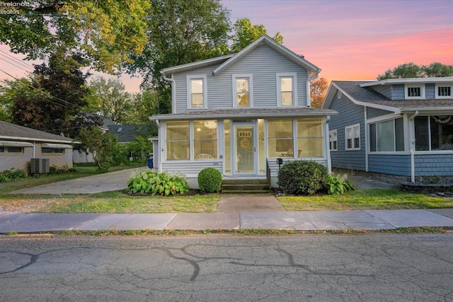 traditional-style house with central AC unit and a sunroom