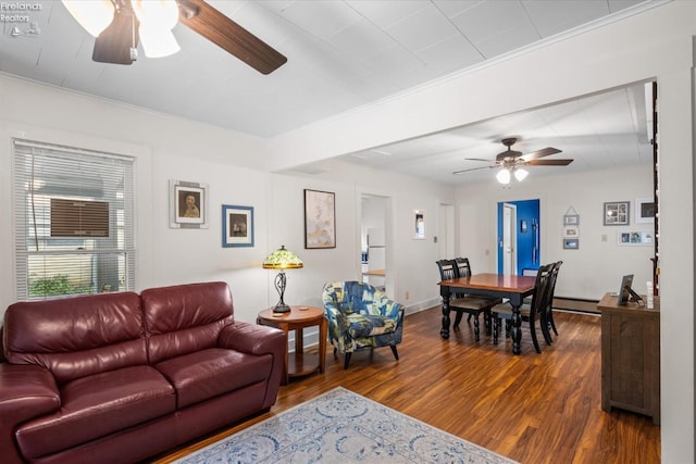 living area with a baseboard radiator, baseboards, wood finished floors, and a ceiling fan