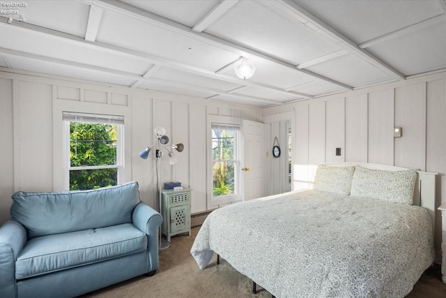 bedroom featuring baseboard heating, multiple windows, a decorative wall, and carpet