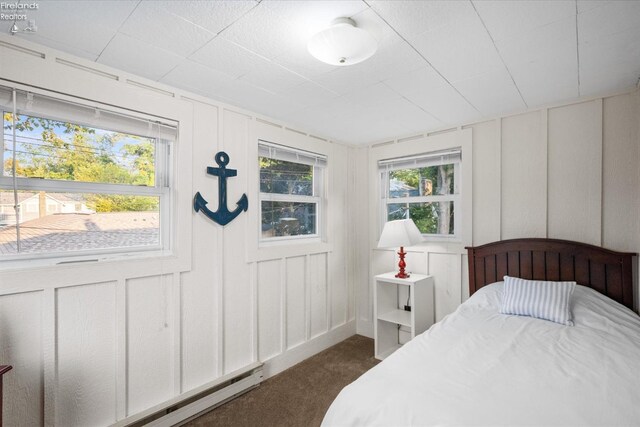 bedroom featuring a decorative wall, dark colored carpet, and baseboard heating