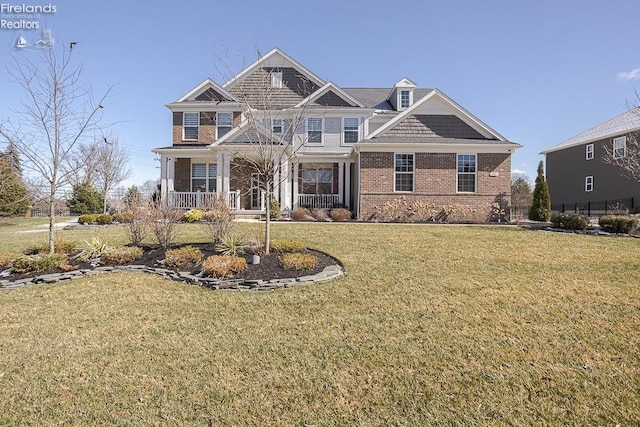 view of front facade featuring brick siding, covered porch, and a front yard