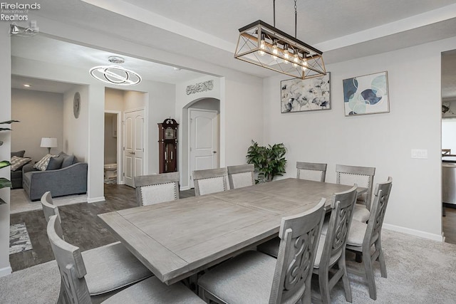 dining room featuring baseboards, arched walkways, a notable chandelier, and wood finished floors