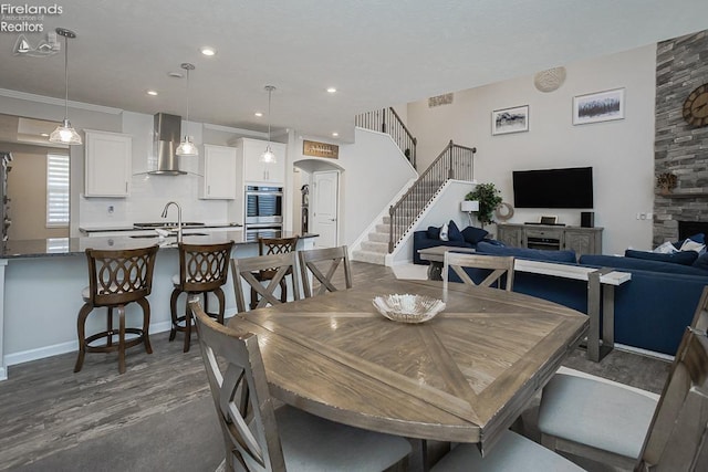 dining area with arched walkways, stairway, dark wood finished floors, and recessed lighting