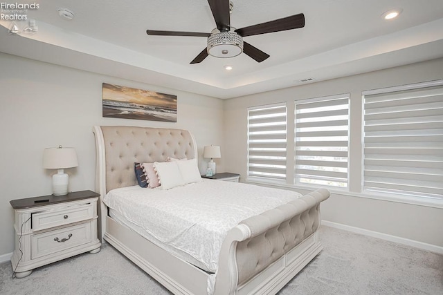 bedroom with visible vents, light carpet, a raised ceiling, recessed lighting, and baseboards