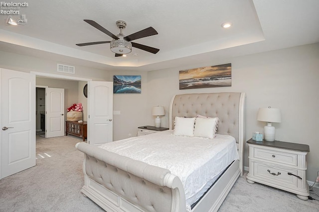 bedroom featuring light carpet, visible vents, recessed lighting, and a raised ceiling