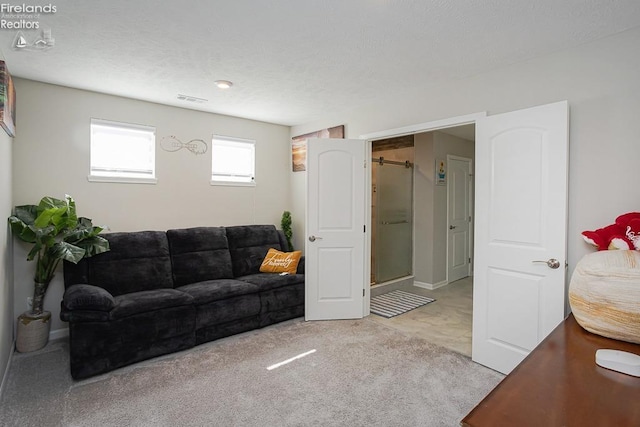 carpeted living area with visible vents and a textured ceiling