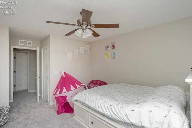 bedroom with baseboards, visible vents, ceiling fan, a textured ceiling, and light colored carpet