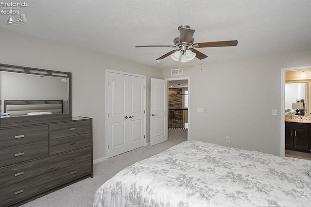 bedroom with a closet, visible vents, ensuite bath, and ceiling fan