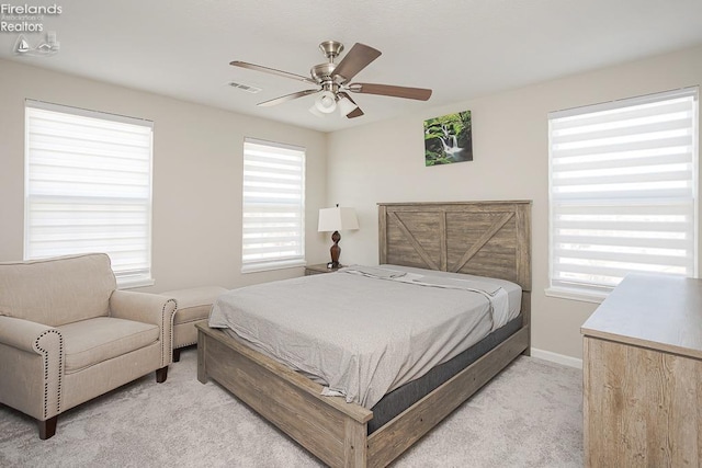 bedroom featuring light carpet, visible vents, baseboards, and a ceiling fan