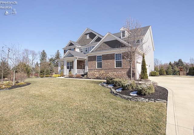 view of front facade featuring an attached garage, covered porch, concrete driveway, a front lawn, and brick siding