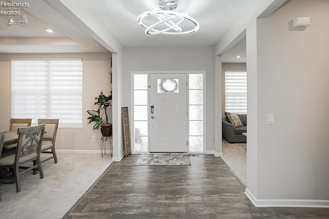 foyer entrance with baseboards, a healthy amount of sunlight, wood finished floors, and an inviting chandelier