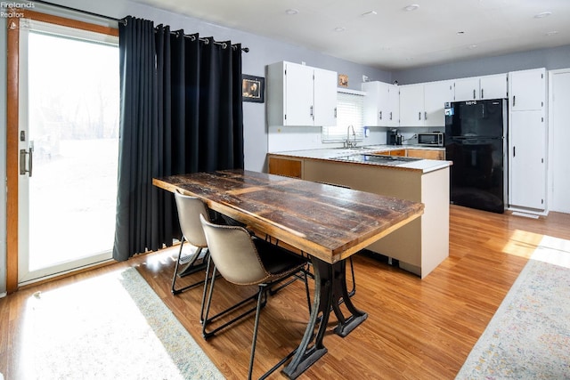 5041 State Route 99, Monroeville, OH 44847 - kitchen with stainless steel microwave, freestanding refrigerator, white cabinets, light wood finished floors, and light countertops