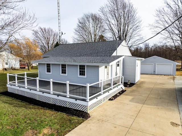 back of property featuring a garage, an outbuilding, roof with shingles, and a lawn