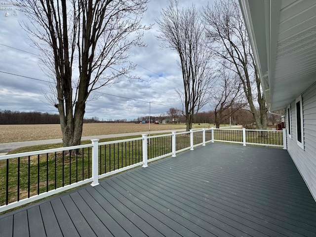 wooden deck featuring a rural view and a lawn