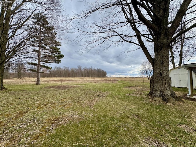 view of yard with a shed, a rural view, and an outdoor structure