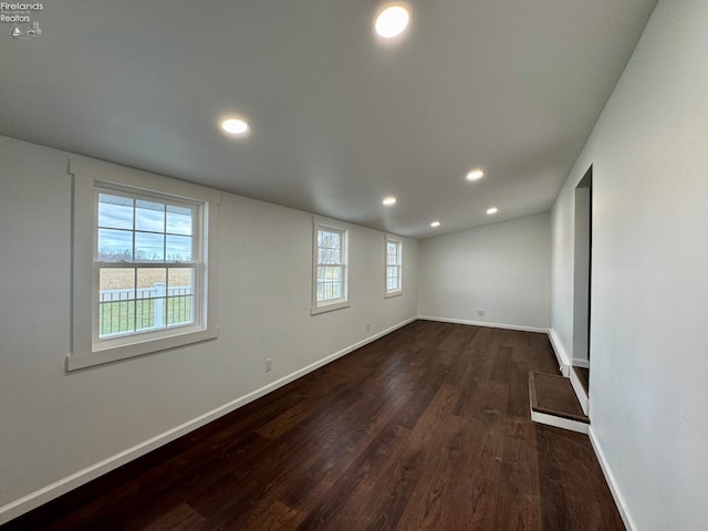 empty room featuring dark wood-type flooring, recessed lighting, and baseboards