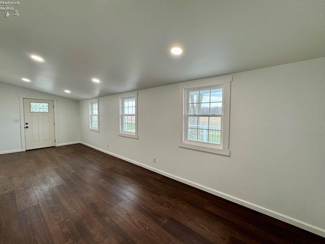 spare room with lofted ceiling, recessed lighting, baseboards, and dark wood-style flooring