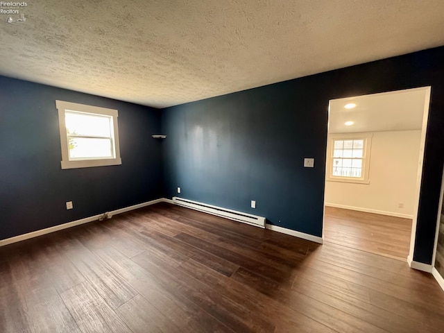 empty room with plenty of natural light, a baseboard heating unit, baseboards, and wood finished floors
