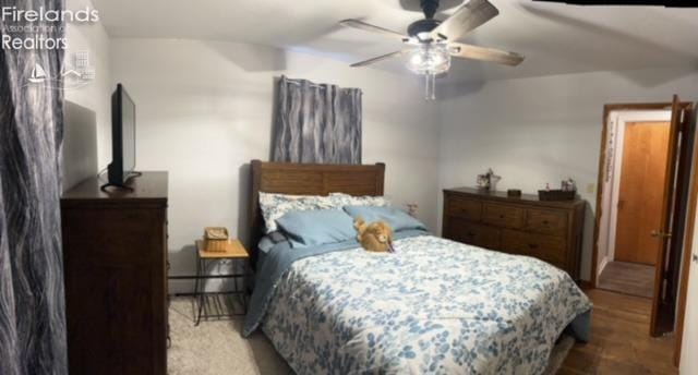 bedroom featuring a baseboard radiator, wood finished floors, and ceiling fan