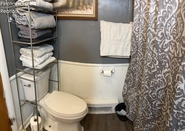 full bathroom featuring toilet, a shower with curtain, and wood finished floors