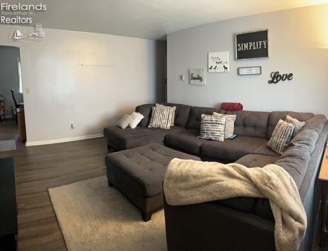 living room featuring baseboards, lofted ceiling, and wood finished floors