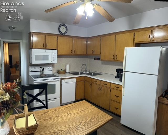 kitchen with light countertops, a sink, brown cabinetry, white appliances, and ceiling fan