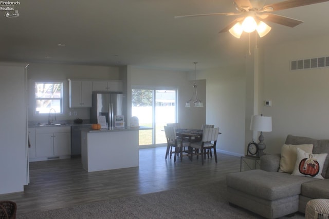 living area featuring visible vents, dark wood-type flooring, and a ceiling fan