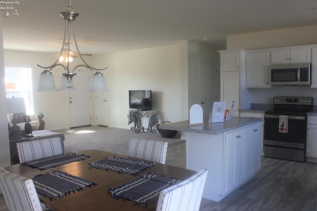 kitchen featuring light countertops, appliances with stainless steel finishes, white cabinetry, open floor plan, and a center island