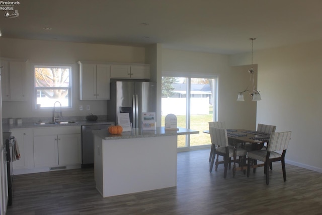 kitchen featuring visible vents, a kitchen island, appliances with stainless steel finishes, white cabinetry, and a sink