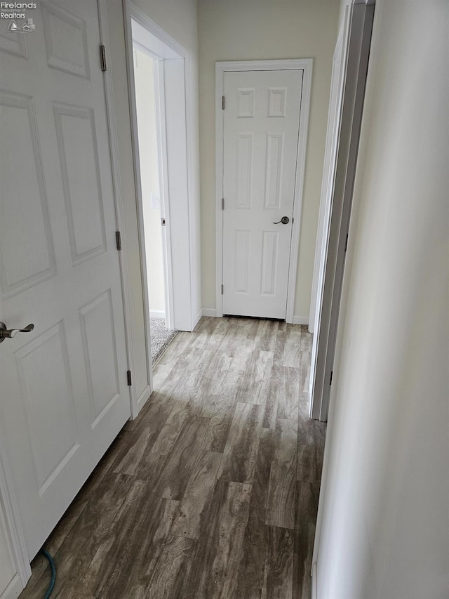 corridor featuring dark wood-style floors and baseboards