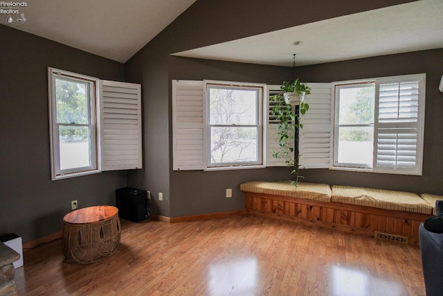 interior space with visible vents, baseboards, light wood-style floors, and vaulted ceiling