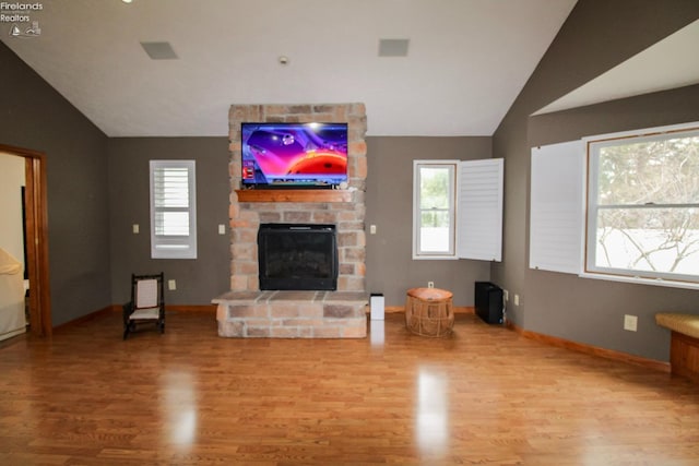living room with a wealth of natural light, wood finished floors, and lofted ceiling