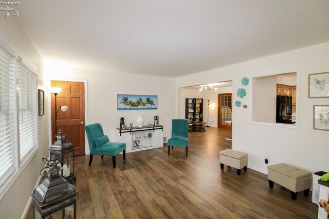 living area with baseboards, an inviting chandelier, and wood finished floors
