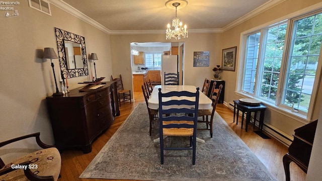 dining area with dark wood-style flooring, baseboards, visible vents, ornamental molding, and an inviting chandelier