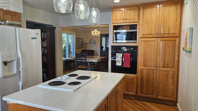 kitchen with white appliances, an inviting chandelier, a center island, light wood-style flooring, and brown cabinetry