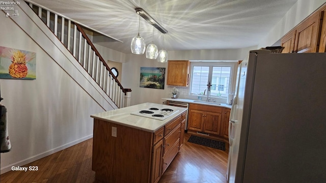 kitchen with light countertops, white appliances, a center island, a sink, and brown cabinetry