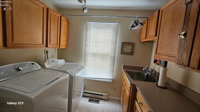 washroom with a sink, washing machine and clothes dryer, cabinet space, visible vents, and a baseboard heating unit