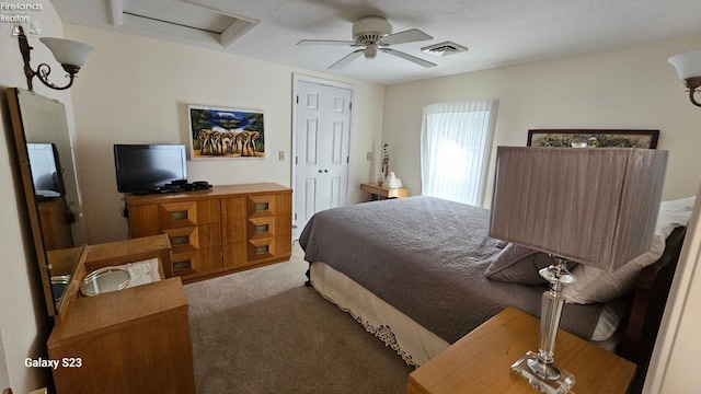 bedroom featuring attic access, visible vents, carpet floors, and a ceiling fan