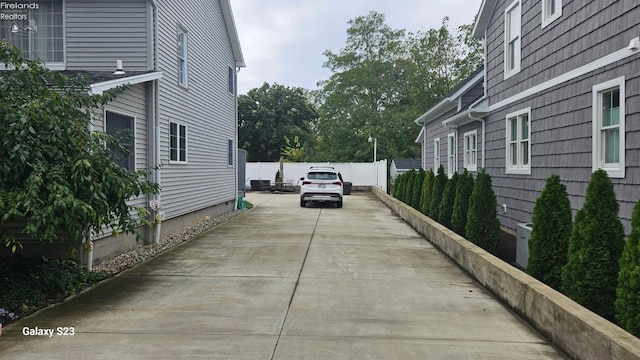 view of side of home with driveway and fence