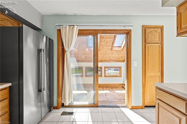 doorway to outside with light tile patterned floors, a textured ceiling, baseboards, and visible vents