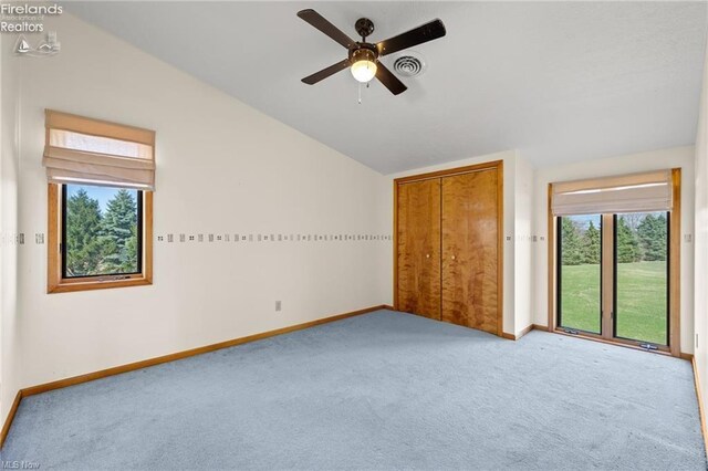unfurnished bedroom featuring baseboards, vaulted ceiling, a closet, and carpet